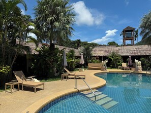 A pool area with lounge chairs, a statue, and a thatched-roof structure. - Tropical Garden Kamala Resort (Kamala)