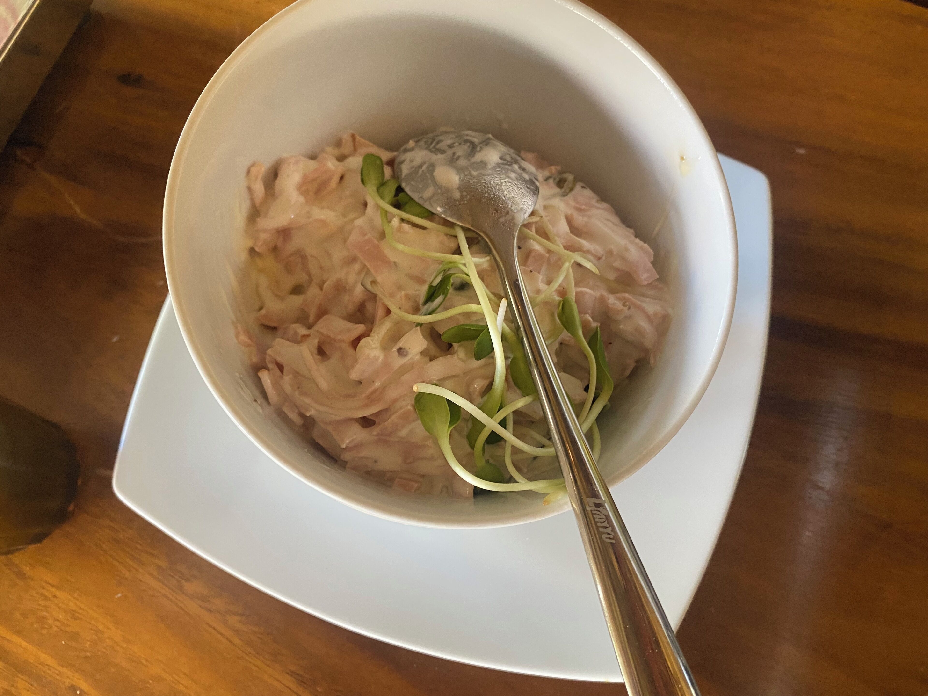 Eine Schüssel mit Essen und einem Löffel auf einem weißen Teller.