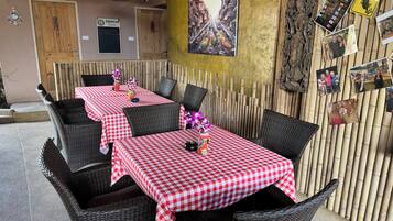 Un restaurante con manteles a cuadros, sillas de mimbre y un muro de bambú.