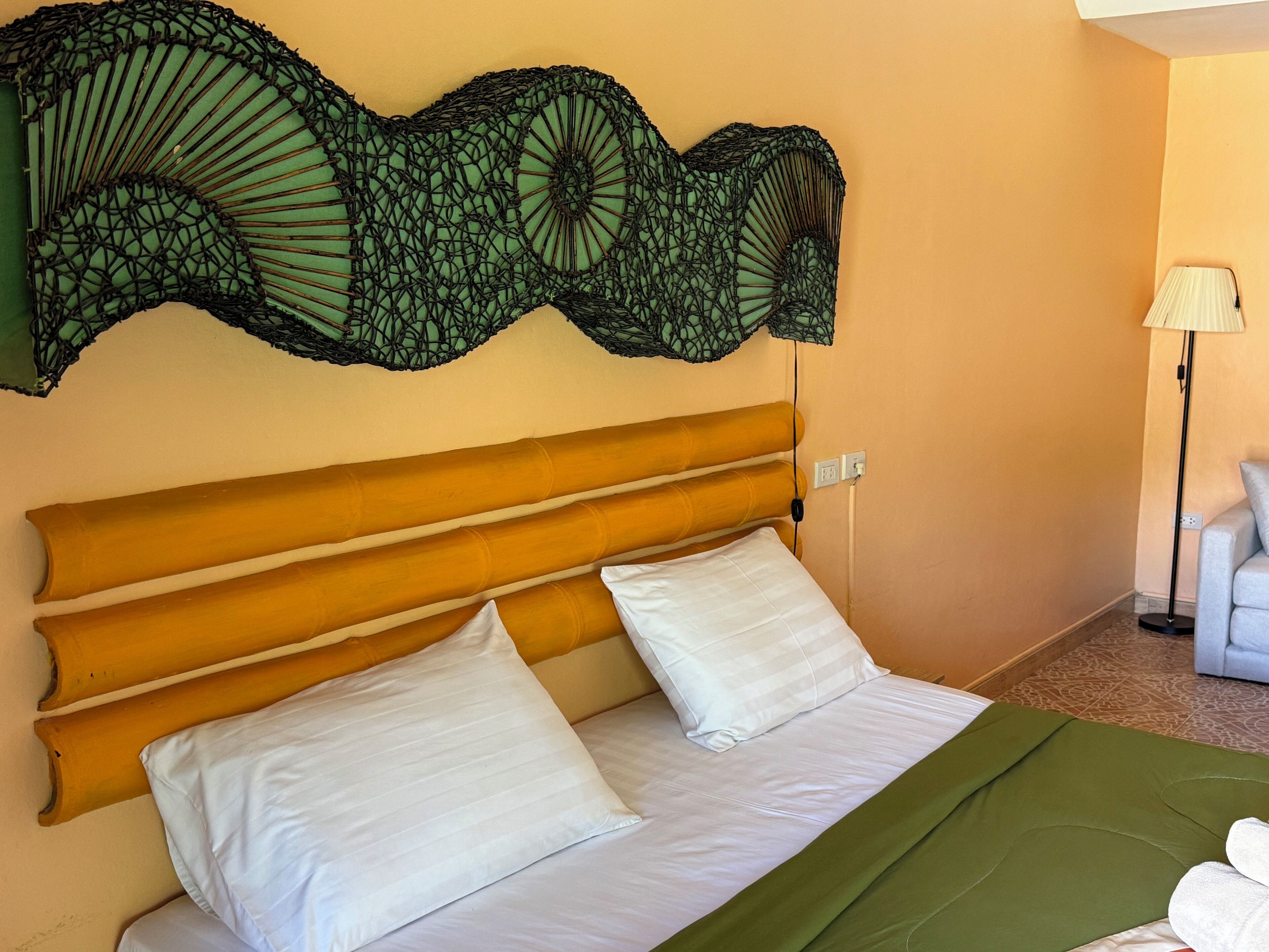 A bed with a wooden headboard, white pillows, and a green bedspread.
