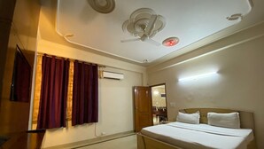 Un dormitorio con cama, ventilador de techo, equipo de aire acondicionado y espejo.