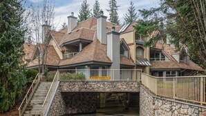 Une maison à plusieurs étages, dotée d’une entrée en pierre, d’un panneau indiquant la hauteur maximale autorisée pour le passage des véhicules et d’un escalier menant à l’entrée.