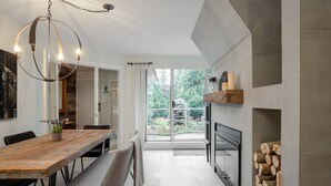 Une cuisine moderne dotée d’une grande fenêtre, d’une cheminée intégrée et d’un coin repas avec une table et un banc en bois.