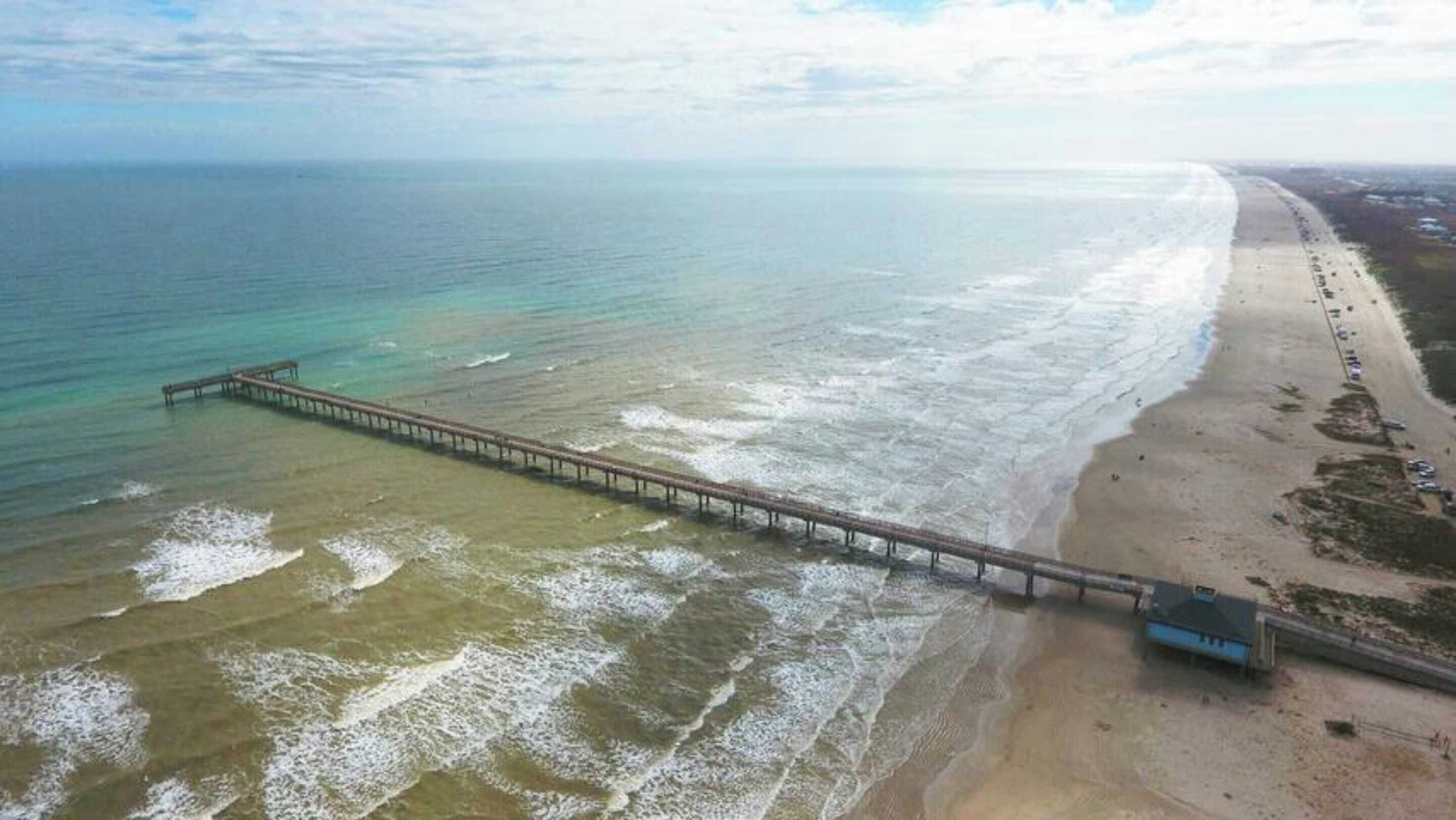 A beach with a long pier extending into the ocean.