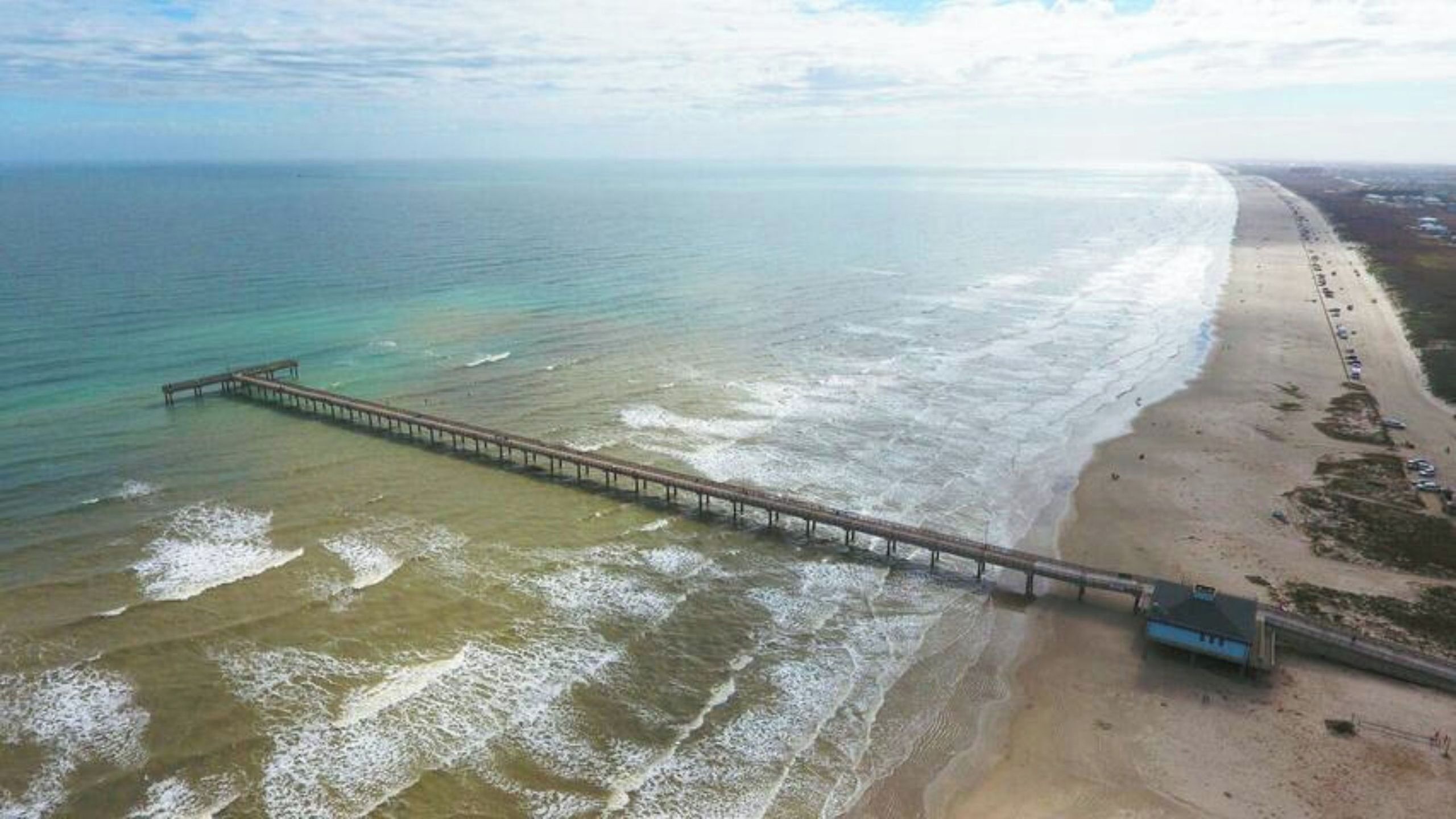 A beach with a long pier extending into the ocean.