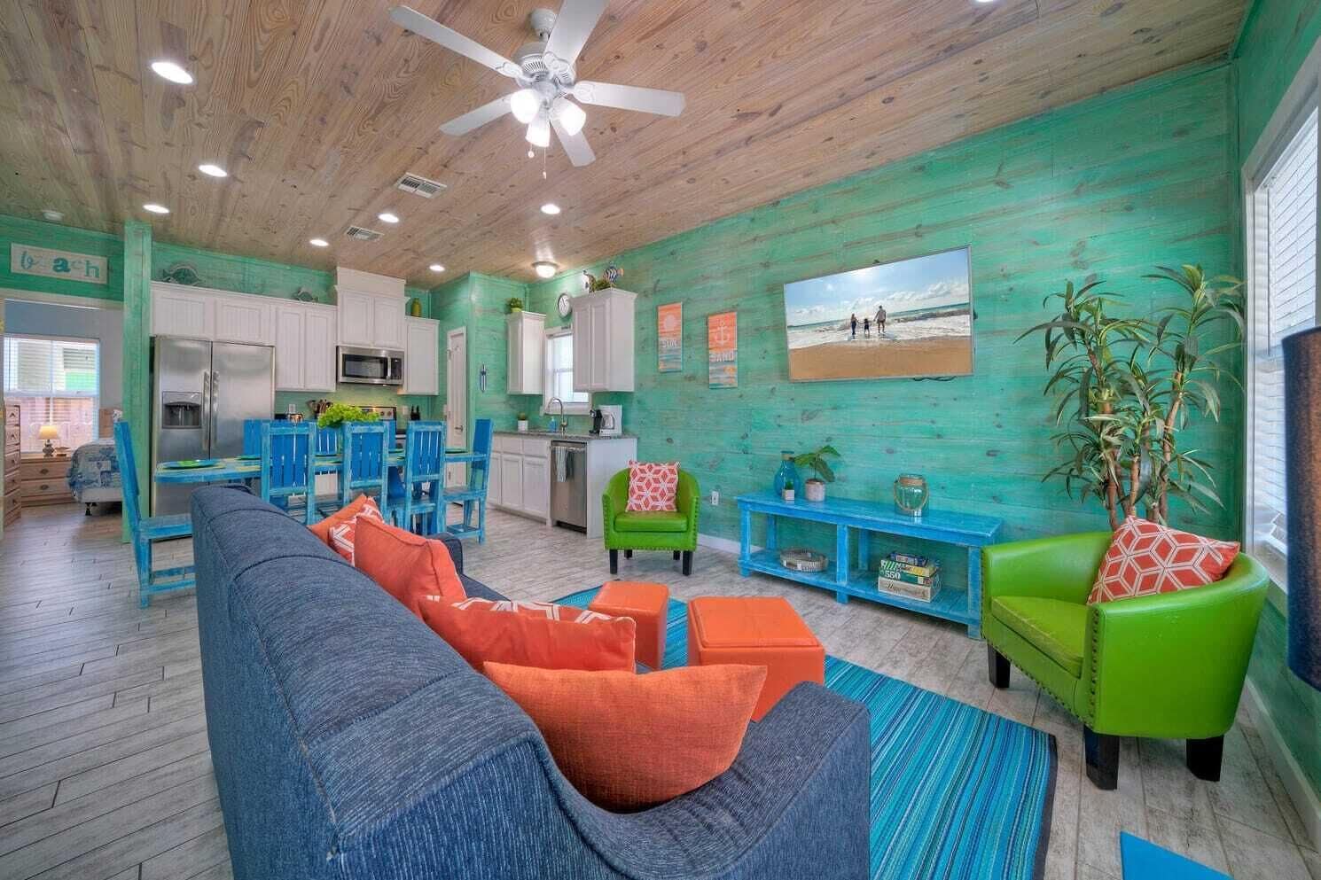 A spacious living area with a blue sofa, green armchairs, and a dining area with blue chairs.