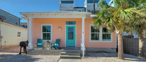 A single-story house with a porch, a door, and a small table with chairs.