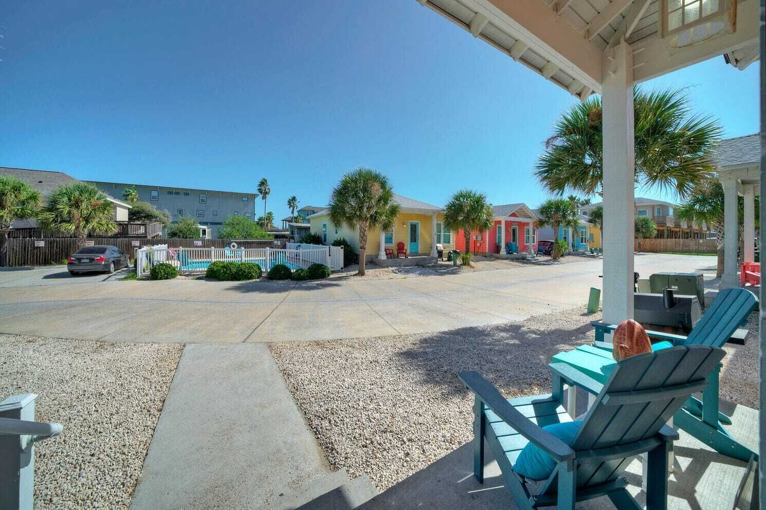 A covered outdoor area with a pool, colorful buildings, and outdoor seating.