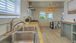 A modern kitchen with a stainless steel sink, wooden countertop, and a hanging pendant light. - Kenna's Kabana by Avantstay Walk to Beach (Port Aransas)