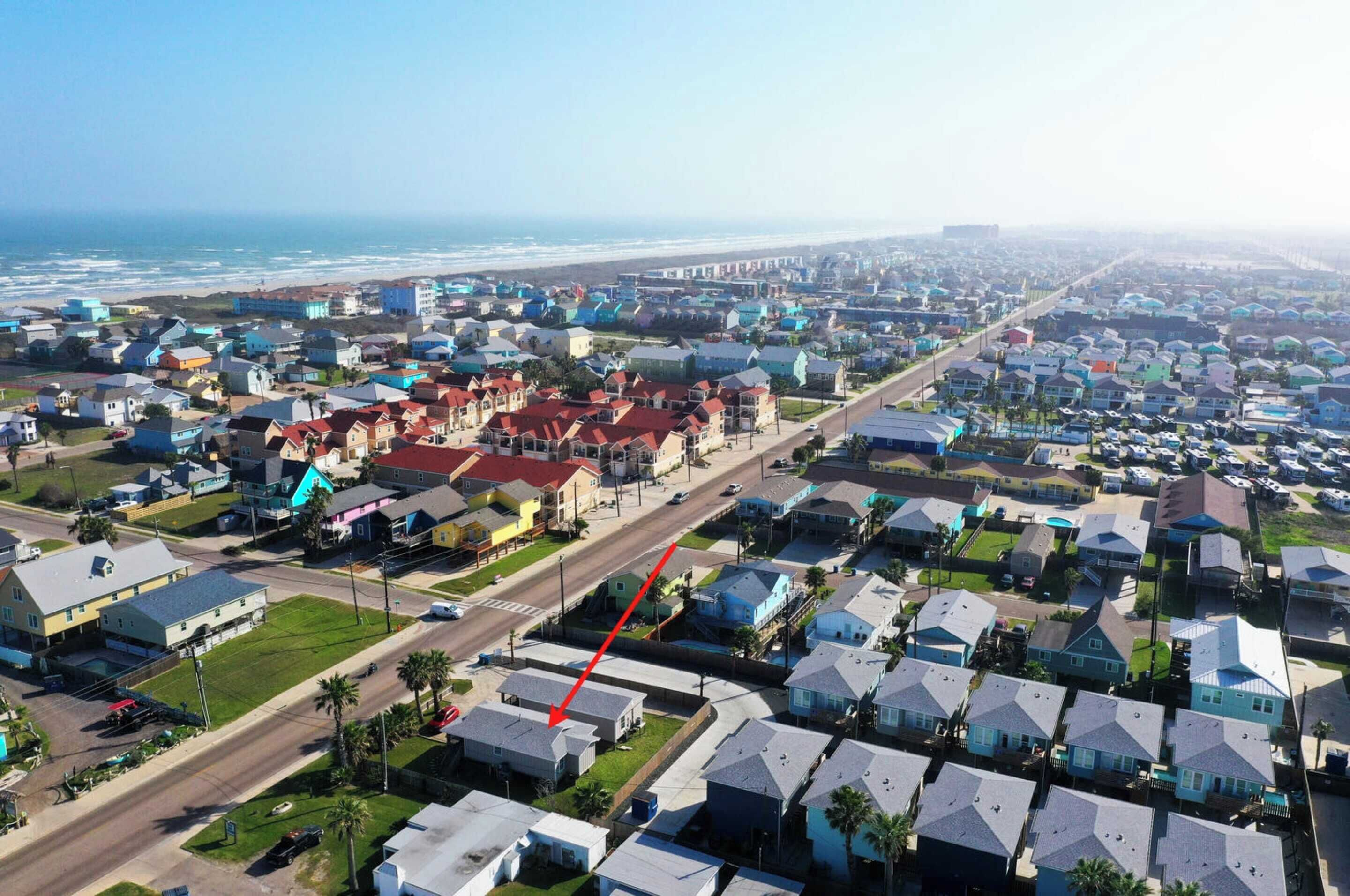 A residential area with houses, roads, and a beach in the background.