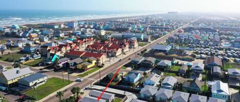A residential area with houses, roads, and a beach in the background.