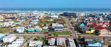 A coastal residential area with houses, a road, and a beach in the background.