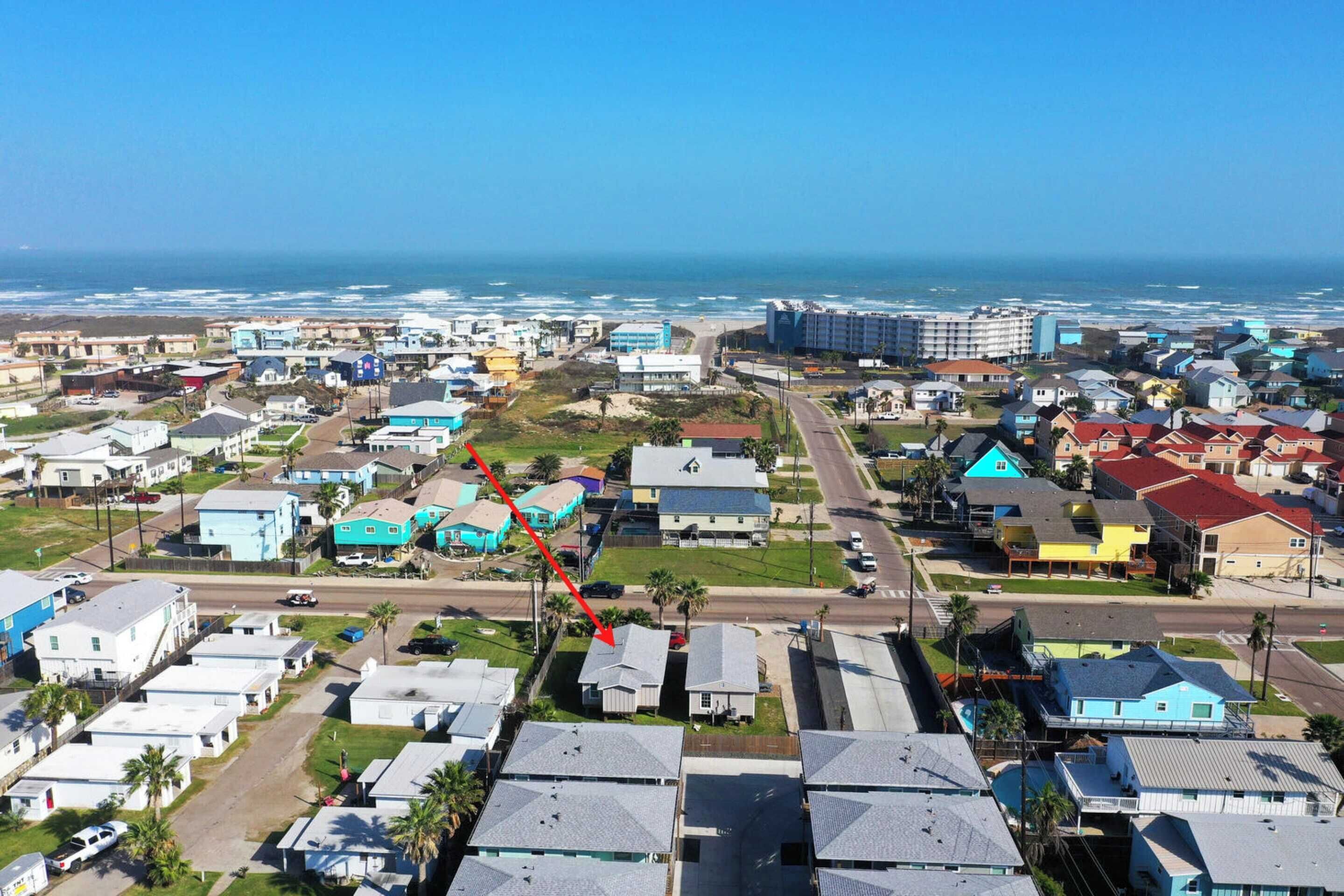 A coastal residential area with houses and a road leading to the beach.