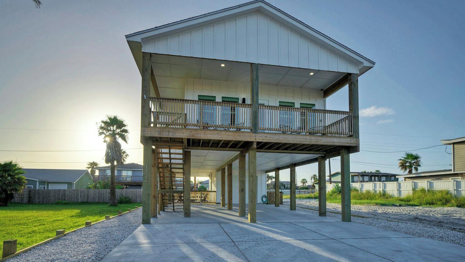 A two-story building with a balcony, a wooden deck, and a concrete walkway.