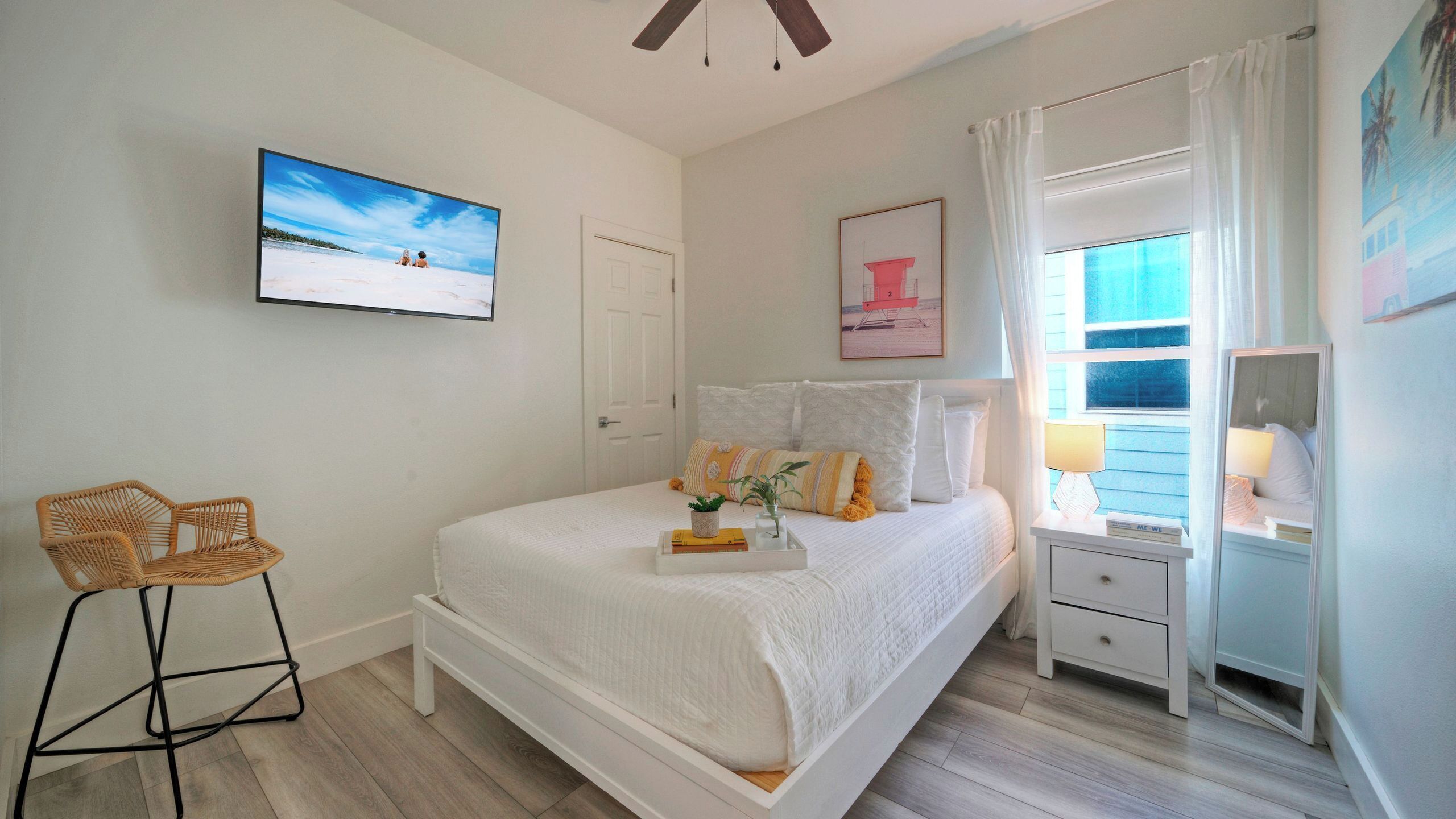 Um quarto com uma cama, uma cadeira, uma mesa de cabeceira, um espelho e uma janela com cortinas.