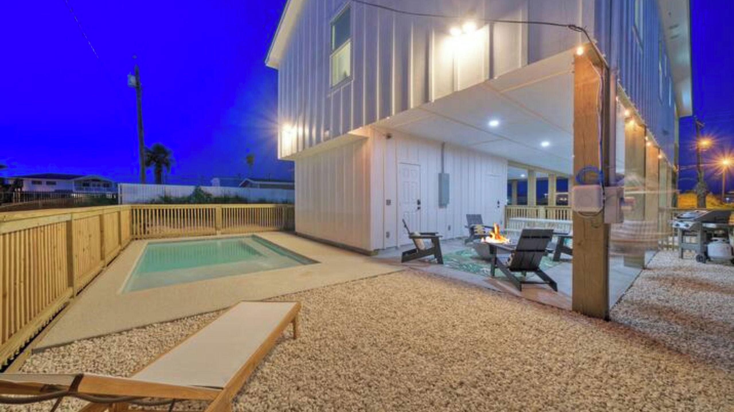 A pool area with a hot tub, lounge chairs, and a covered deck.
