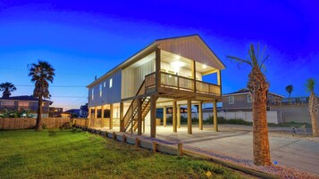 A two-story house with a balcony, a staircase, and a well-lit exterior.