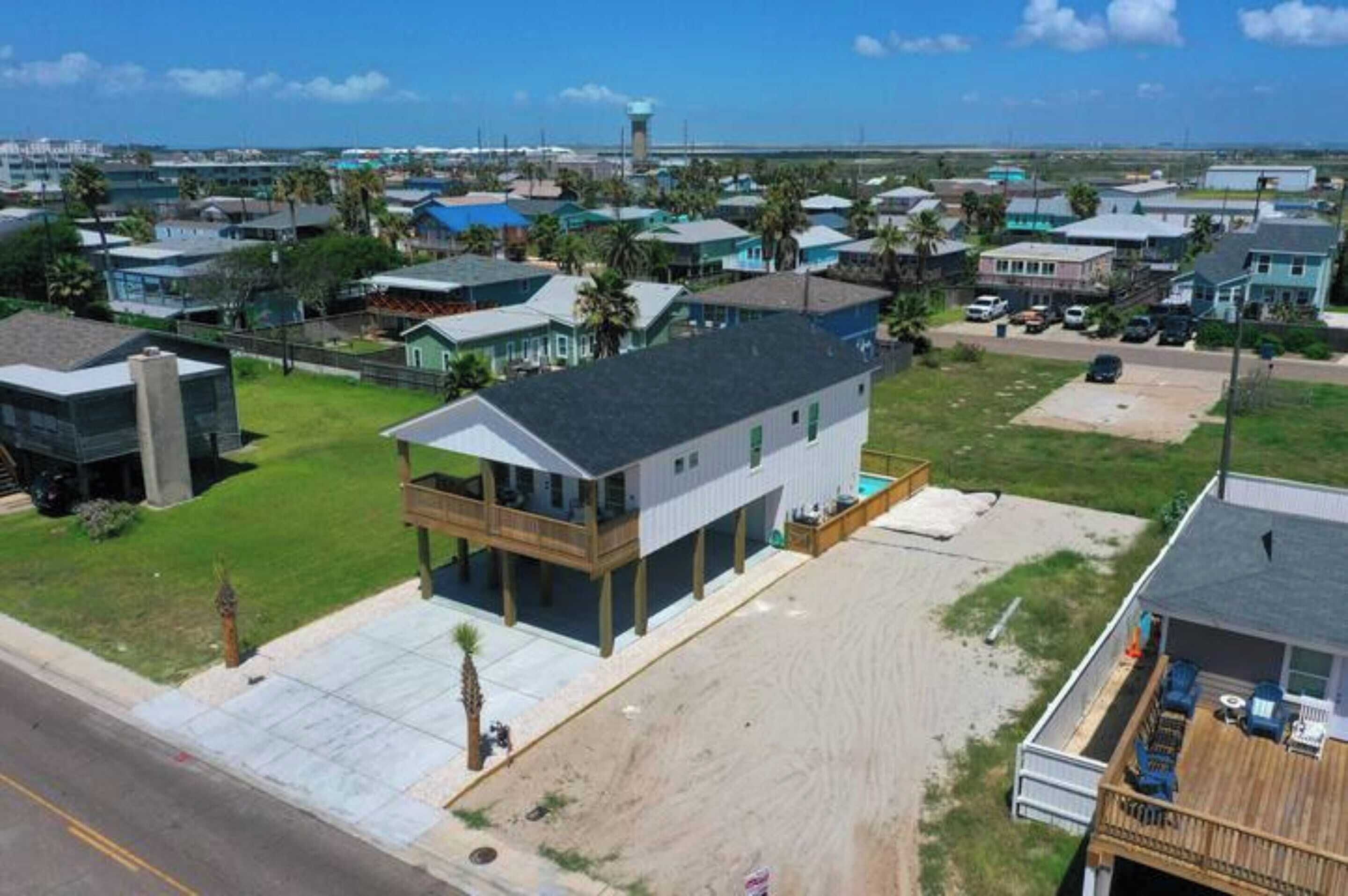 A coastal residential area with houses, a beach, and a lighthouse in the background.