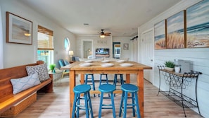 A spacious kitchen with a central island, bar stools, a sofa, and a dining table. - Peyton's Place by Avantstay Walk to Beach (Port Aransas)