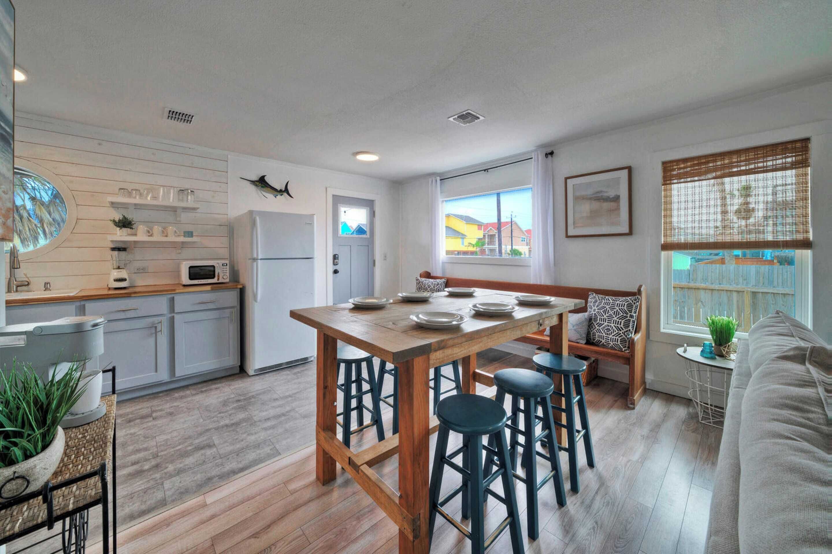 A modern kitchen with wooden countertops, a central island with stools, and a view of the outside through large windows.