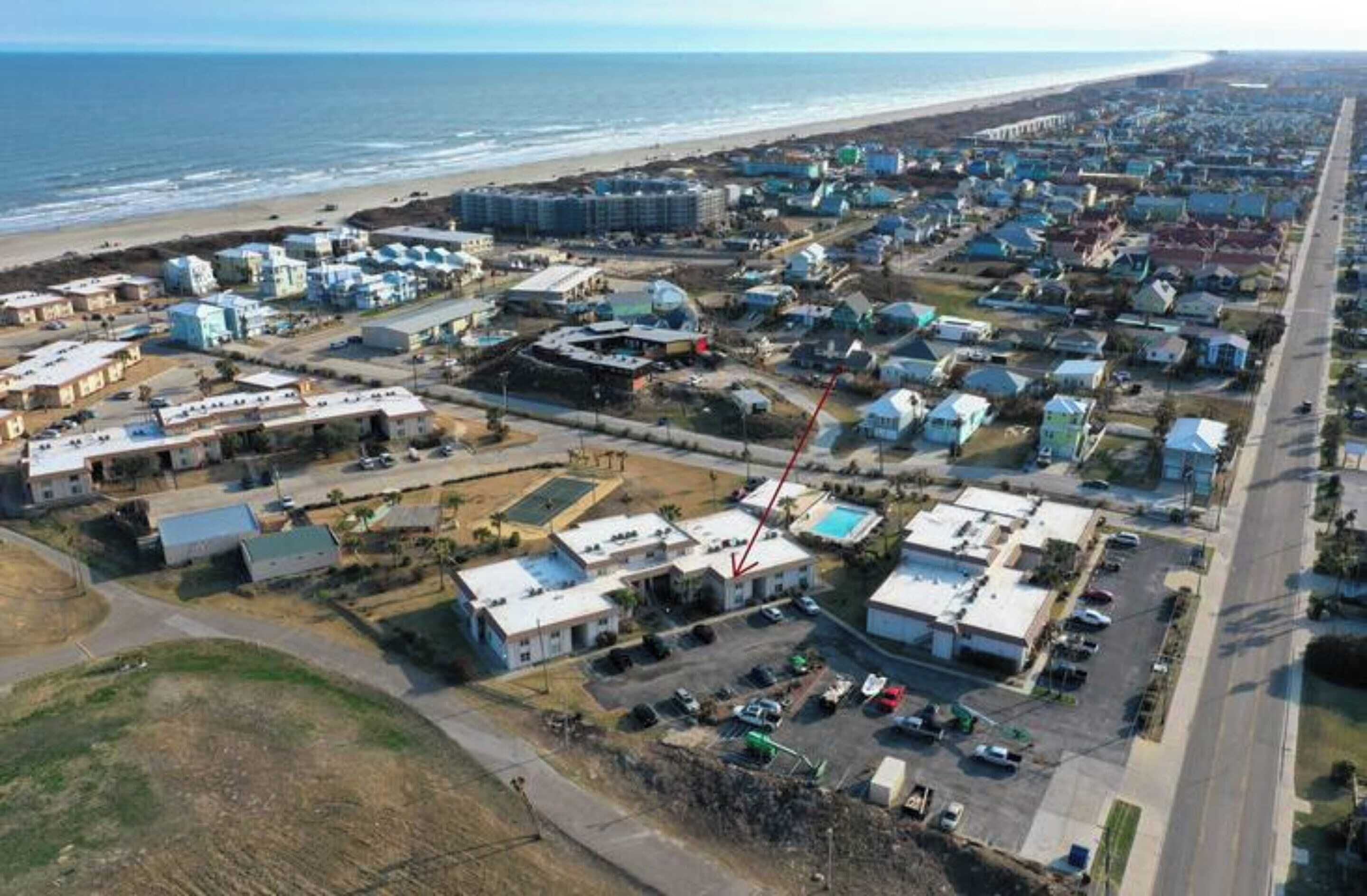 Luftaufnahme einer Küstenwohngegend mit Häusern, Strand und Straße.
