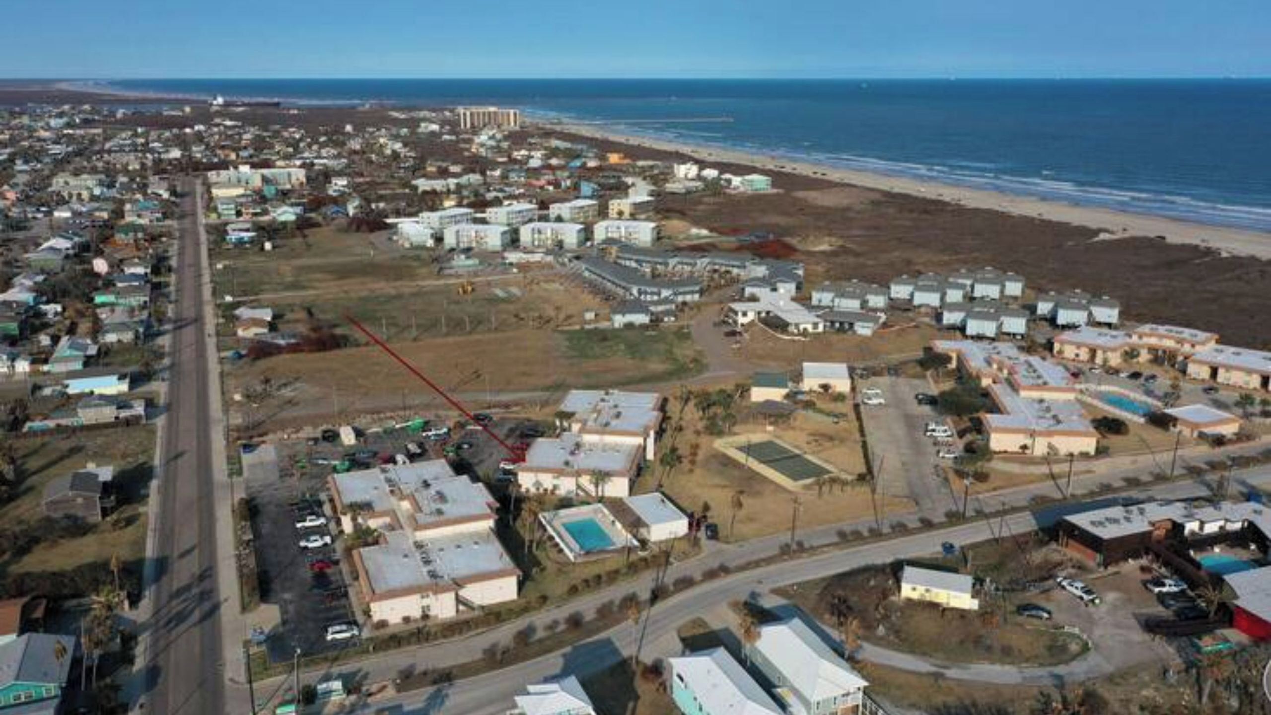 Luchtbeeld van een kustgebied met huizen, een strand en een weg.