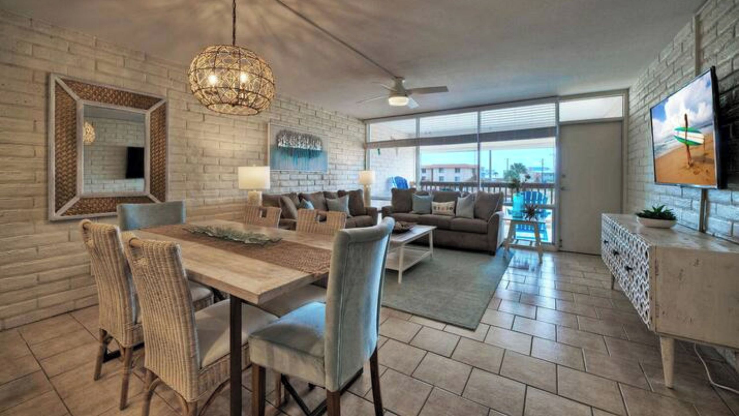 A modern living room with a dining area, large windows, and a TV.