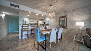 Una cucina moderna con mobili bianchi, una zona pranzo con sedie blu e un grande lampadario.