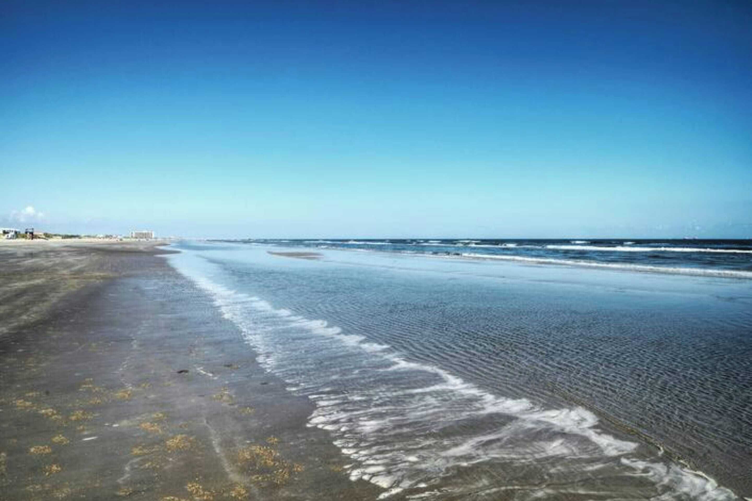 Una playa con una amplia orilla de arena y olas suaves.