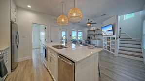 Een moderne keuken met een centraal eiland, roestvrijstalen apparatuur en hanglampen.