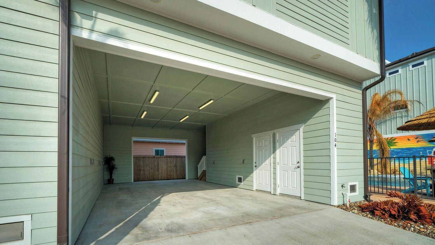 A covered garage with a concrete floor, a wooden door, and a small window.