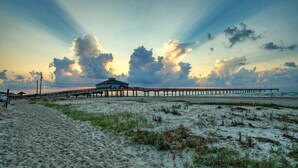 A beach with a pier extending into the sea, a building on the pier, and a clear sky with clouds. - Outdoor Lounge w/ Bar Swing Seats, Near Nature Preserve Blutopia by Avantstay (Port Aransas)