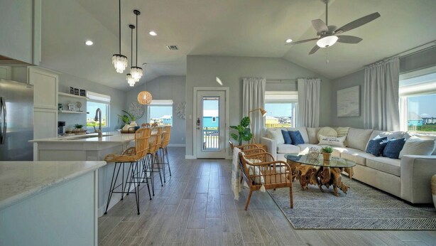 A modern kitchen with a dining area, a living room with a sofa and coffee table, and a ceiling fan. - Outdoor Lounge w/ Bar Swing Seats, Near Nature Preserve Blutopia by Avantstay (Port Aransas)
