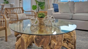 A round glass coffee table with a wooden base, surrounded by wicker chairs and a sofa. - Outdoor Lounge w/ Bar Swing Seats, Near Nature Preserve Blutopia by Avantstay (Port Aransas)