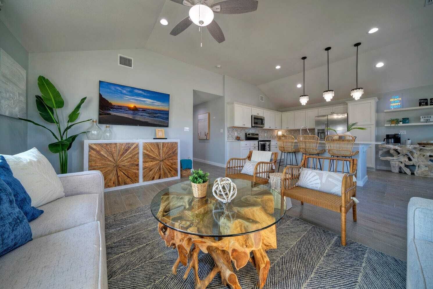 A modern living room with a glass coffee table, comfortable seating, and a large TV.