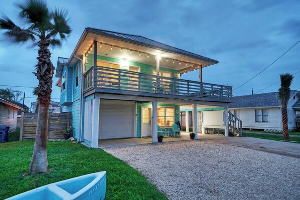 A two-story house with a balcony, a covered porch, and a garage. - Port A Hideaway by Avantstay Private Pool (Port Aransas)