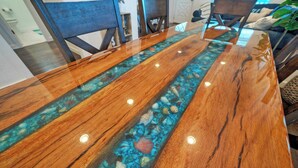 Una mesa de comedor de madera con cubierta de vidrio y un diseño de mosaico azul y blanco.