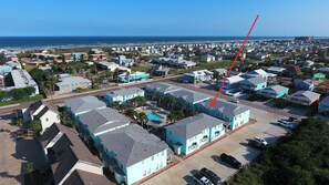 Oversigtsbillede af et boligområde med huse, en swimmingpool og havudsigt.