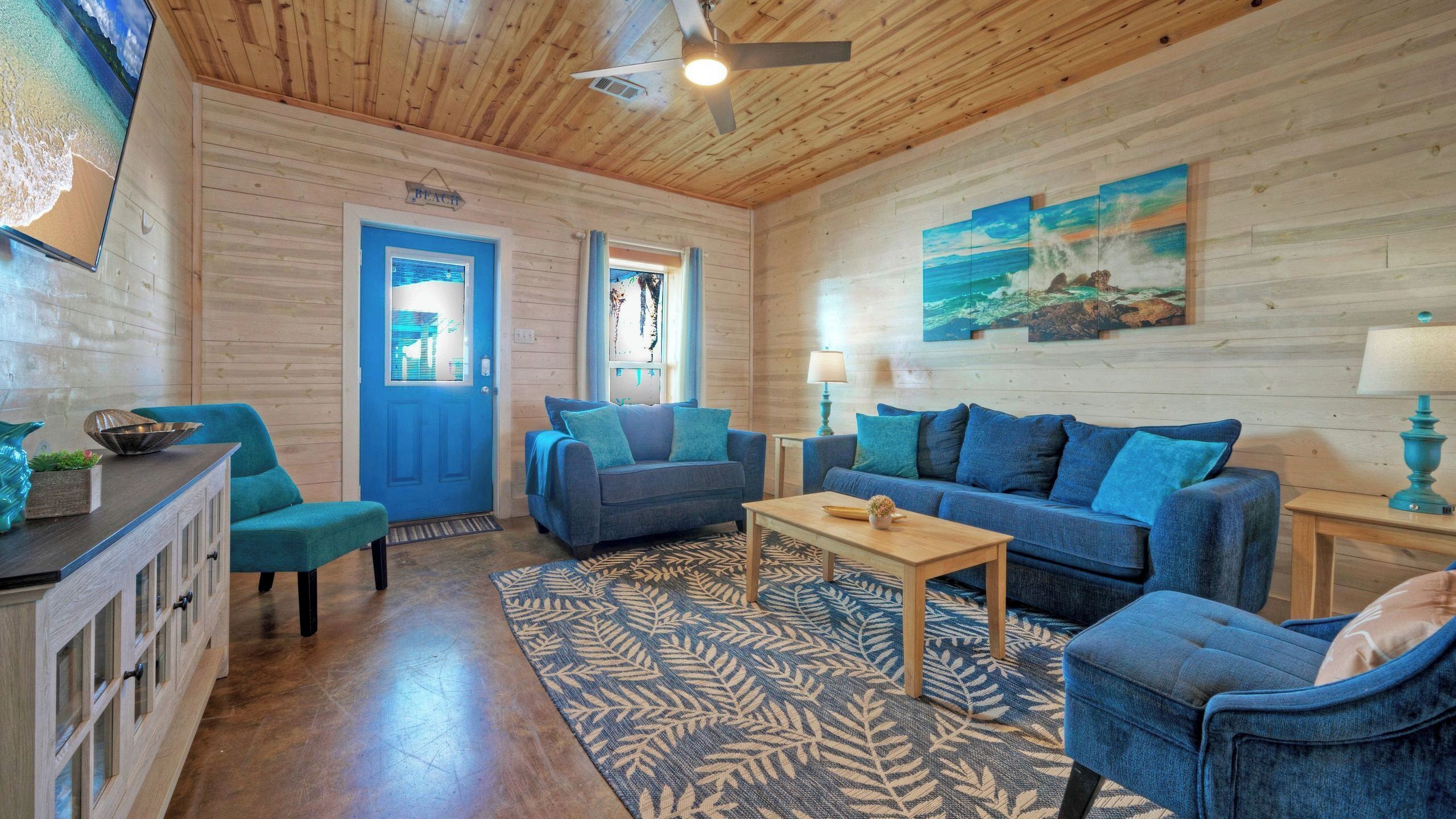 A cozy room with a wooden ceiling, a blue door, and a large window.