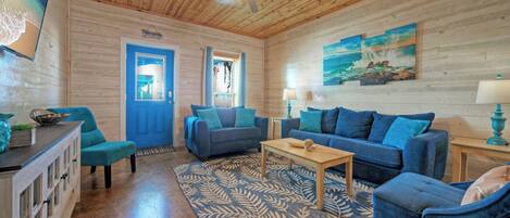 A cozy room with a wooden ceiling, a blue door, and a large window.