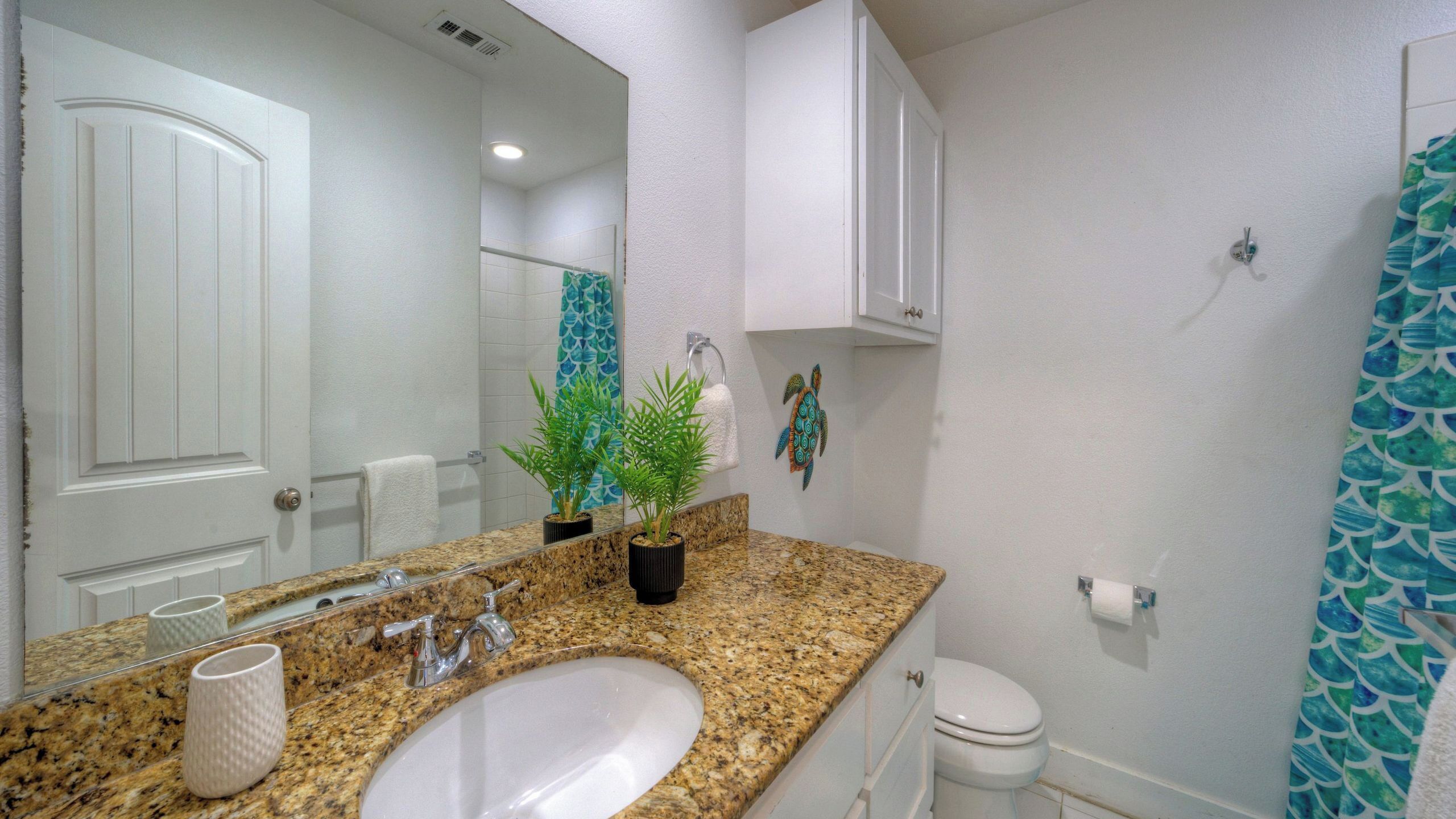 A bathroom with a granite countertop, white sink, and a mirror.