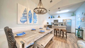 Une cuisine moderne avec une table à manger en bois, des tabourets de bar et un lustre suspendu.