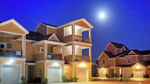 Un immeuble résidentiel à plusieurs étages, doté d’un garage, d’un balcon et d’une entrée bien éclairée.