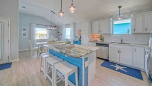 Une cuisine moderne avec des meubles blancs, un îlot central bleu et des luminaires suspendus.
