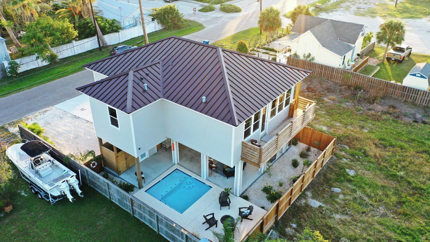 A two-story house with a swimming pool, a boat, and a fenced backyard.
