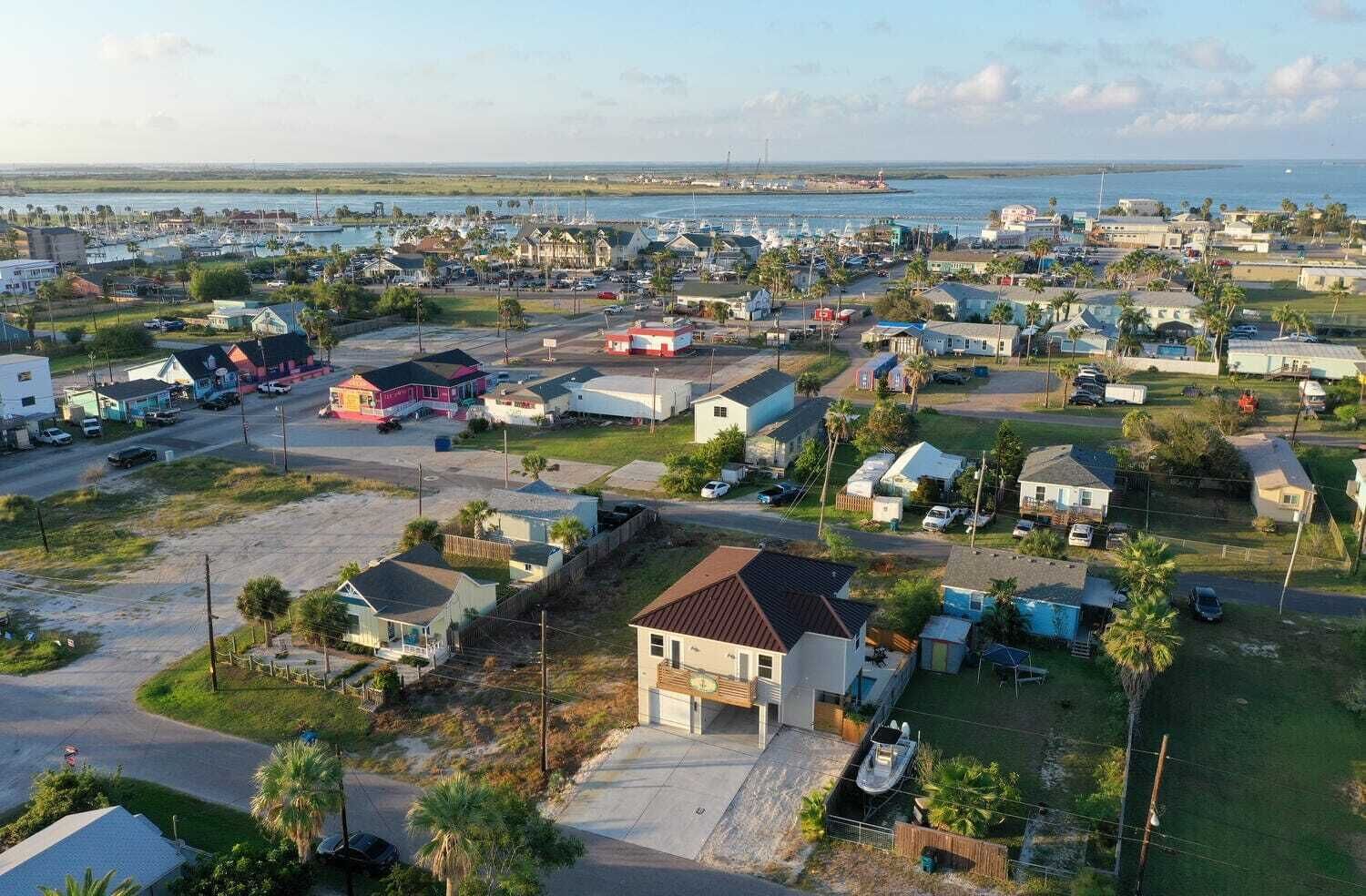 A coastal residential area with houses, a marina, and a view of the ocean.