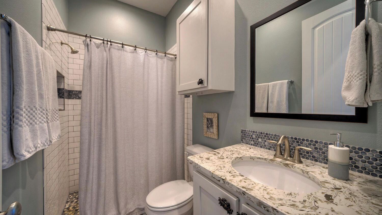 Une salle de bain équipée d’une douche, de toilettes, d’un lavabo et d’un miroir.