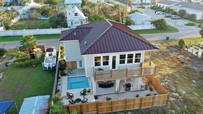 Una casa de dos pisos con piscina, patio trasero cercado y vista al vecindario.