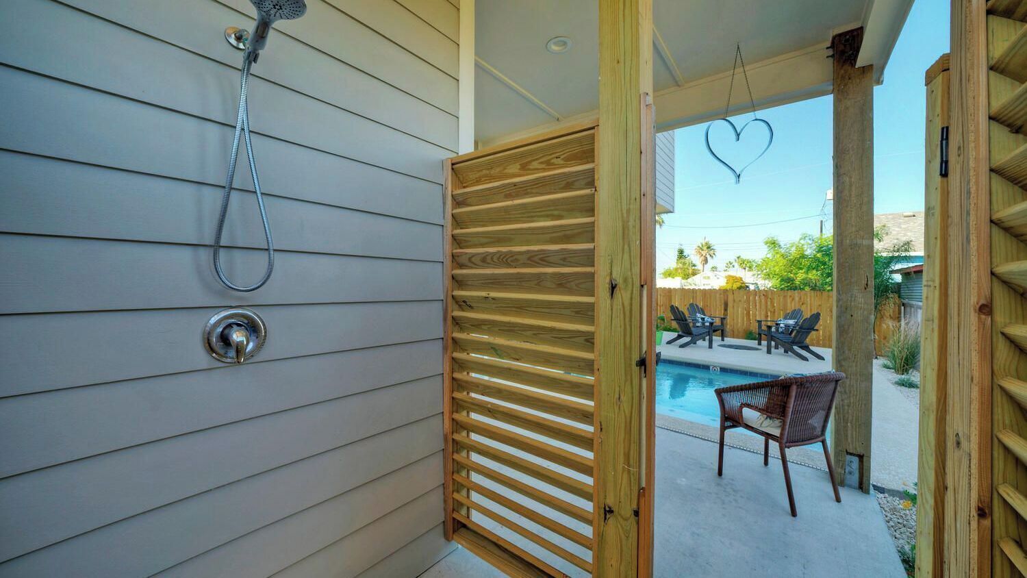 A wooden door leading to a pool area with outdoor furniture.