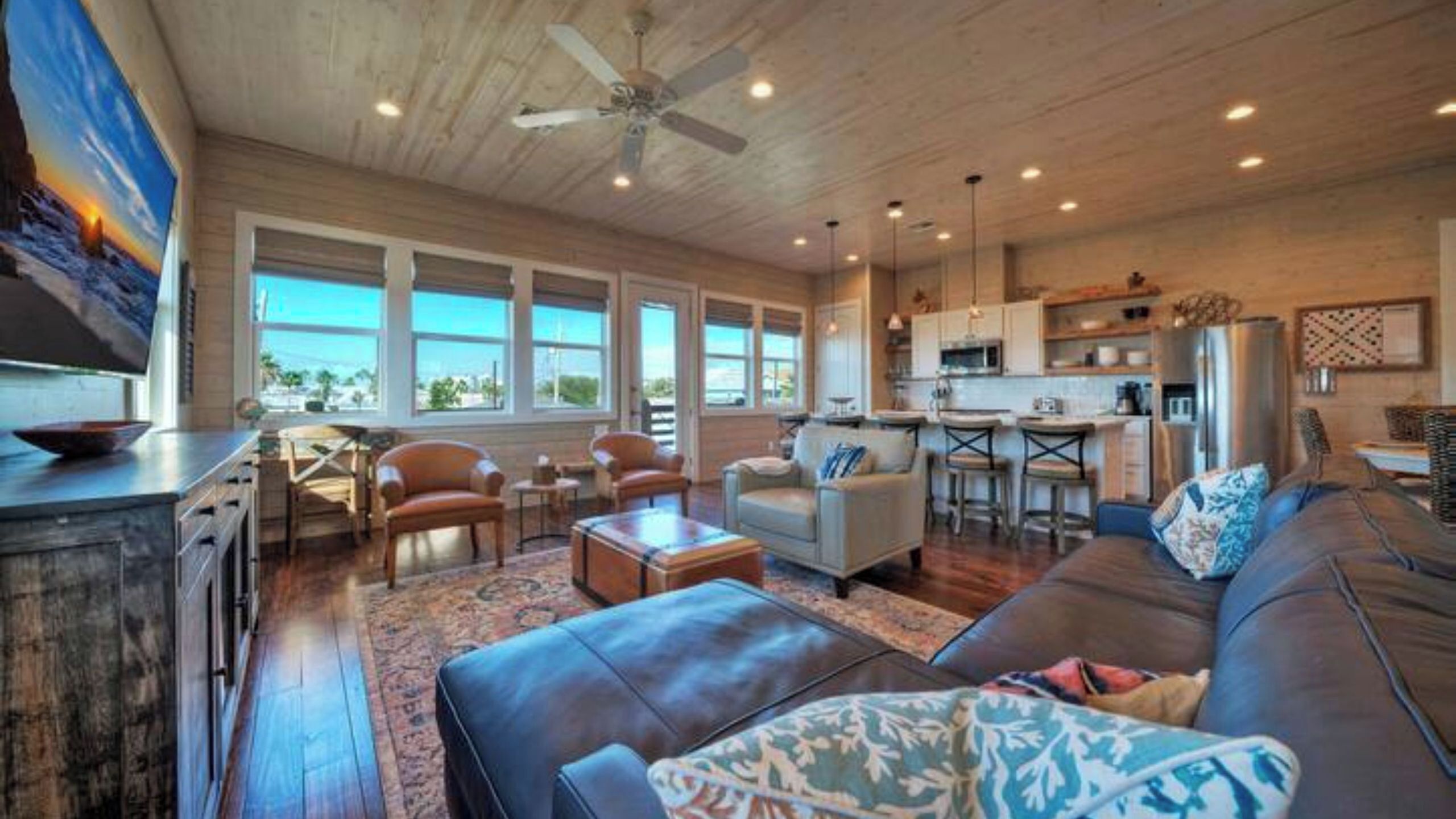 A spacious living area with a large sofa, a dining table, and a kitchen in the background.